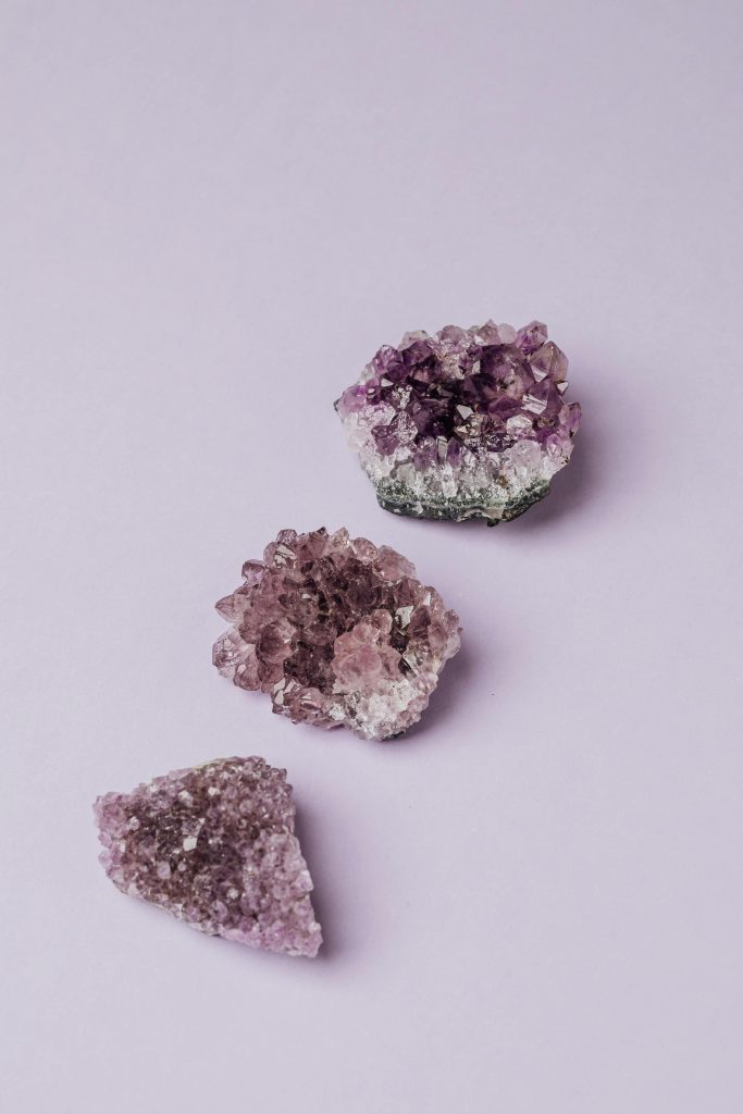 Beautiful amethyst crystals displayed on a light purple surface, showcasing natural beauty.