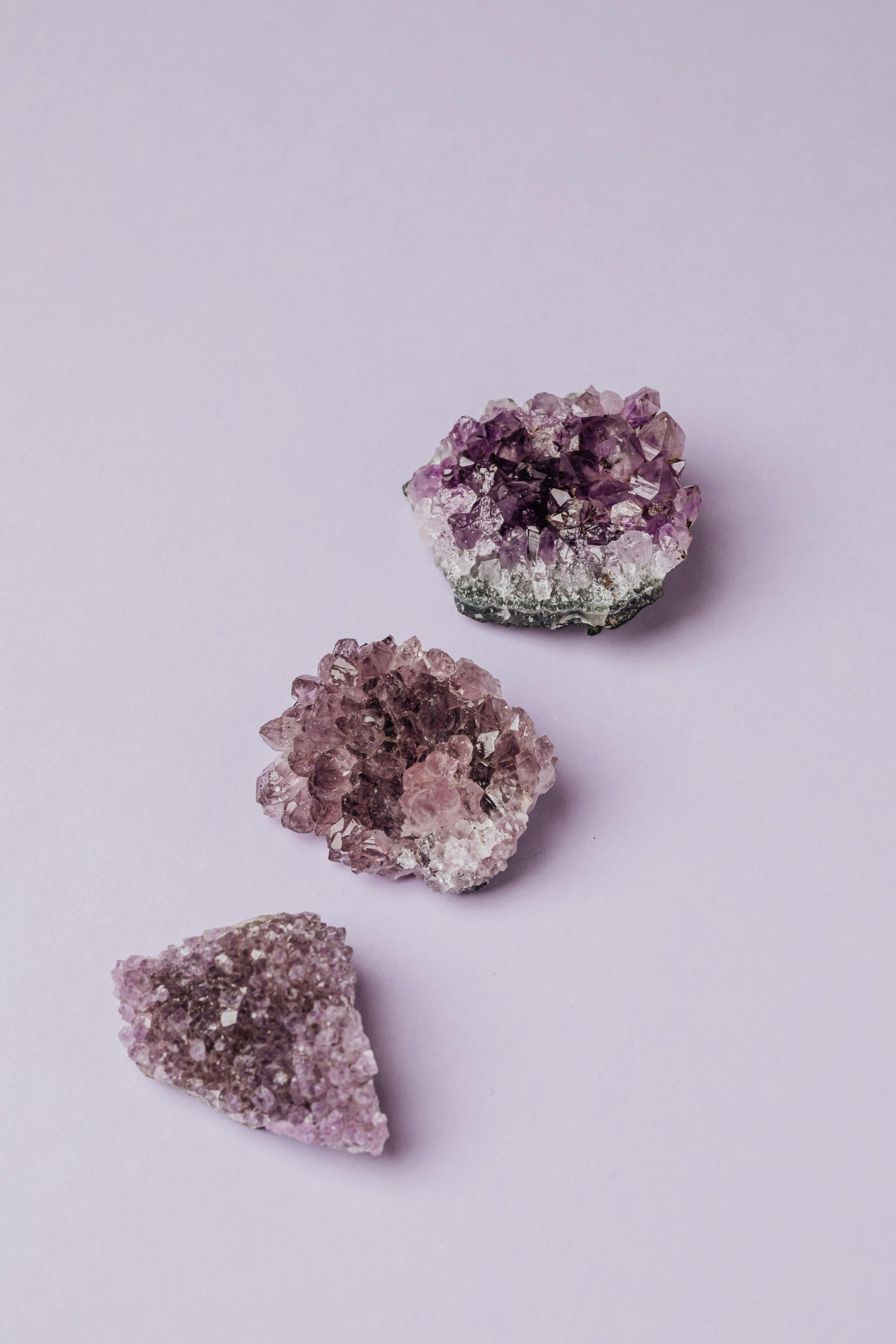 Beautiful amethyst crystals displayed on a light purple surface, showcasing natural beauty.