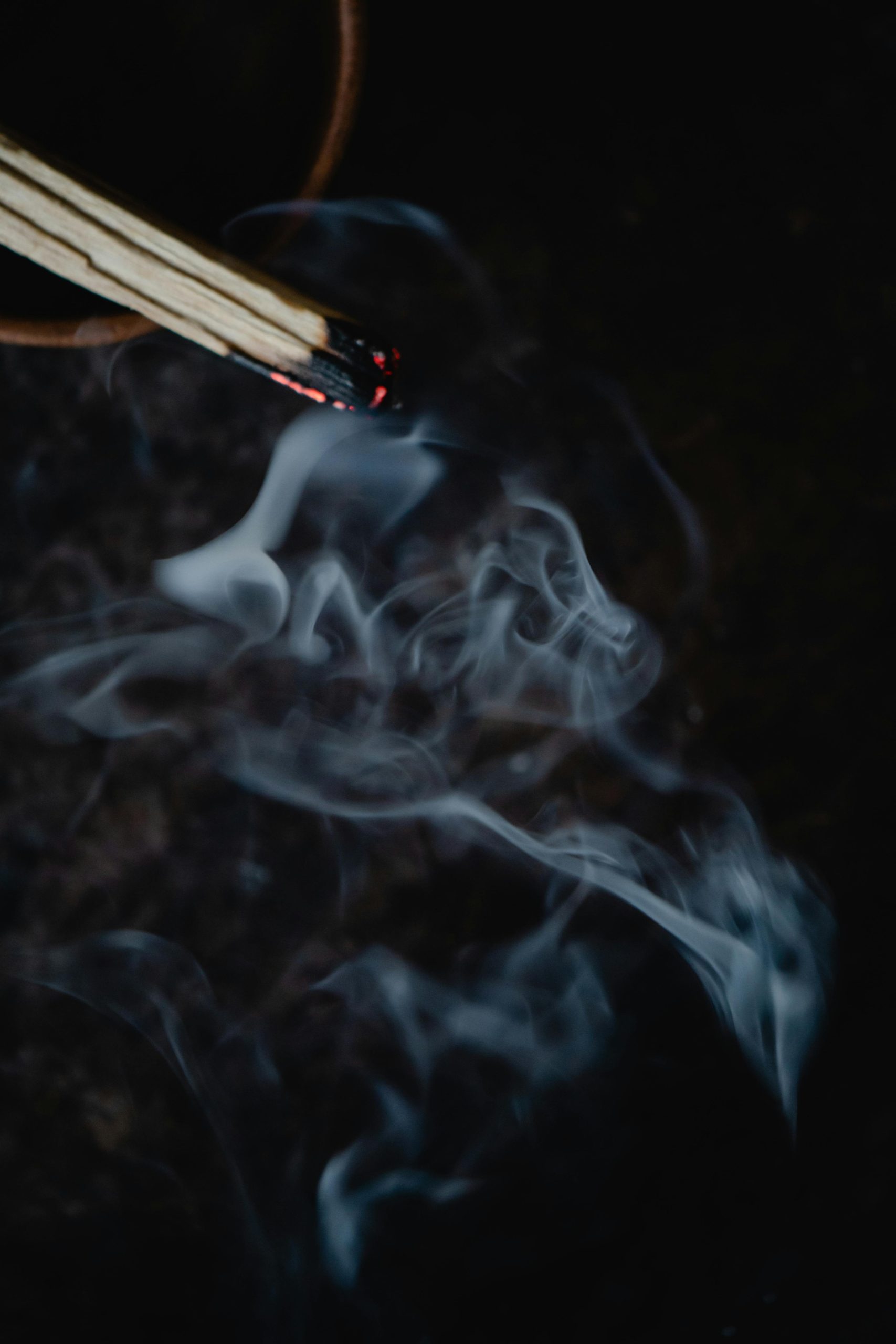 A close-up view of smoke rising from a lit incense stick, evoking a spiritual atmosphere.